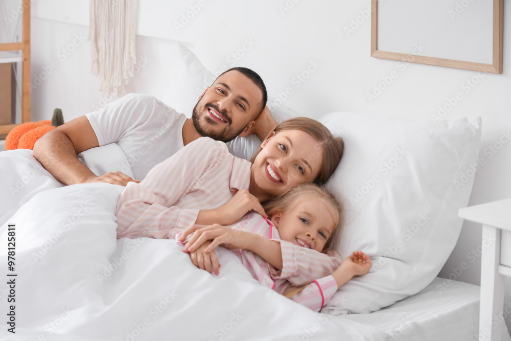 Happy parents with their little daughter lying under soft blanket in bedroom Happy parents with their little daughter lying under soft blanket in bedroom