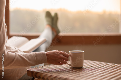 Cuadro en lienzo person relaxing at home reading a book and drinking a cup of hot tea