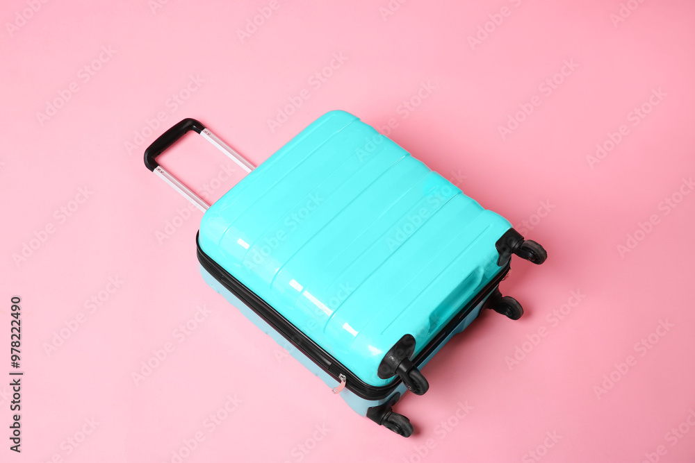 One new turquoise suitcase on pink background, above view One new turquoise suitcase on pink background, above view