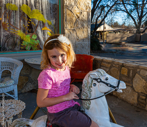 Little Girl Sitting on Toy Pony at The Town Square, Glen Rose, Texas, USA photo