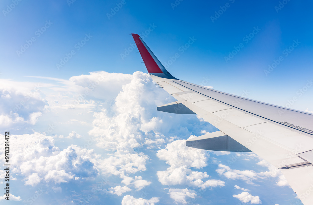Fototapeta premium View from the airplane window at a beautiful cloudy sky and the airplane wing