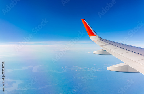 Aerial view from airplane window above green ground. View from the airplane window with beautiful clouds at sunrise