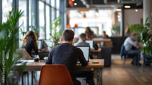 People working on laptops in a modern coworking space with plants and natural light