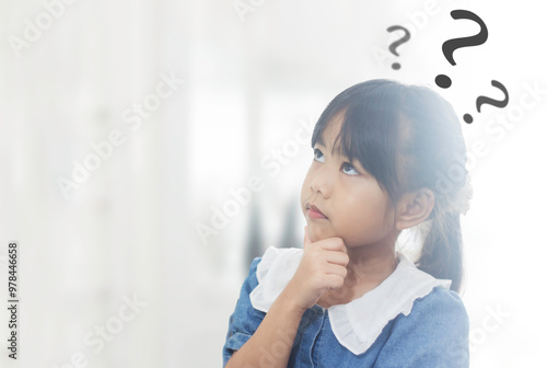 Tablou pe pânză Kid girl Touching his chin with a dubious expression and looking up as if thinking with graphic question marks around her with copyspace