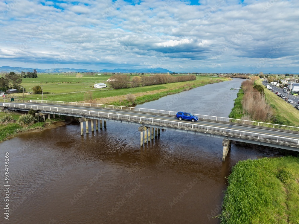 Fototapeta premium Bridge crossing the Waihao River and farmland in Ngatea, Waikato, New Zealand.