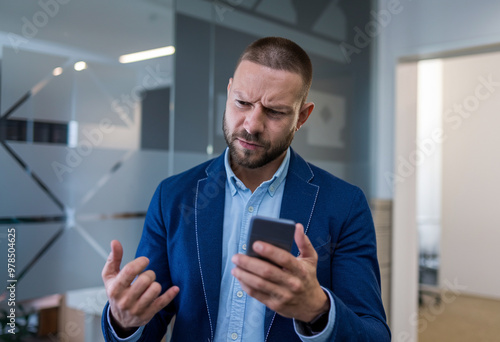 Young Man in Business Suit Experiencing Phone Issue at Workplace