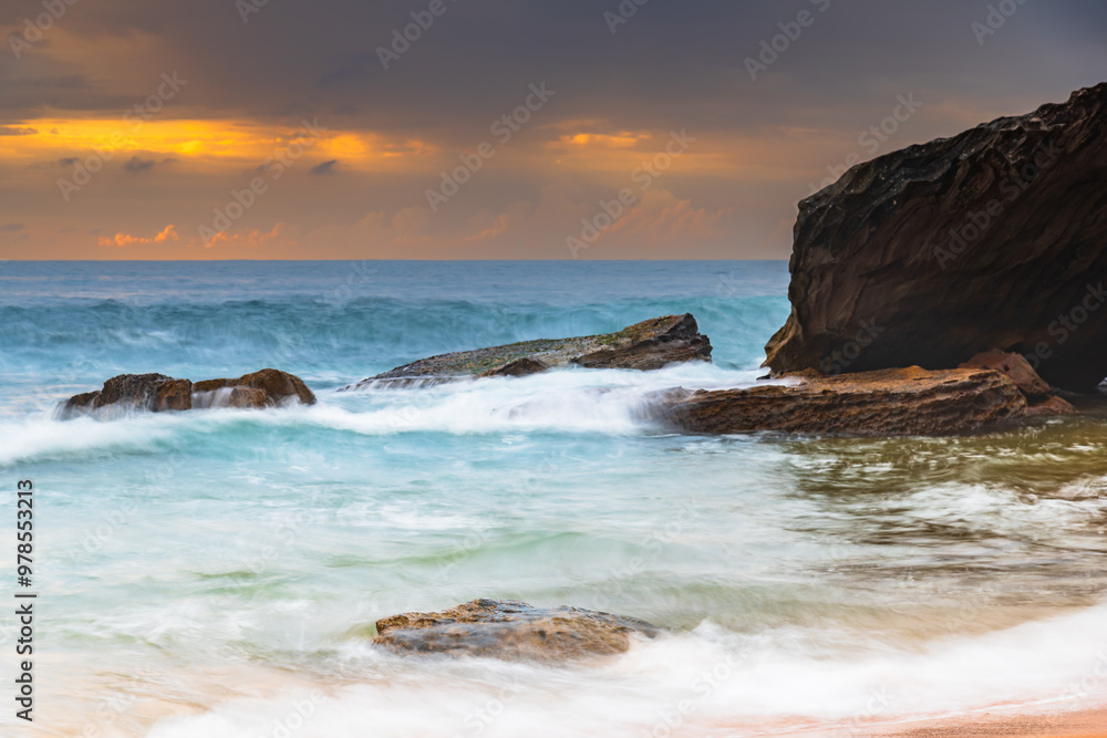 Sunrise at the seaside with rocks and beautiful diffused light by the rain clouds