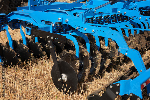 Close-up of a large modern plow blue color or disc harrow for cultivating the land. New model of agricultural equipment.