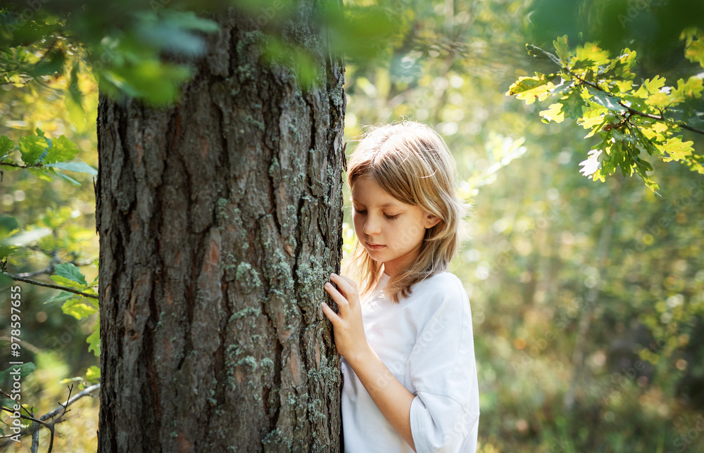Teenager girl hugging tree.