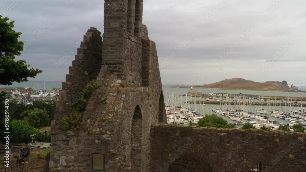 Aerial slow motion dolly orbit around front entrance facade wall of broken brick ruins in Abbey of Howth, Ireland's eye in backdrop Aerial slow motion dolly orbit around front entrance facade wall of broken brick ruins in Abbey of Howth, Ireland's eye in backdrop