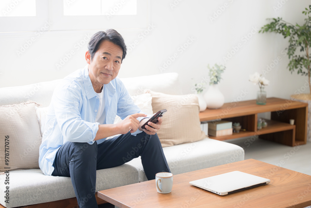 綺麗なリビングでスマホを見るシニア男性の全身 カメラ目線 綺麗なリビングでスマホを見るシニア男性の全身 カメラ目線