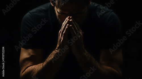 God, worship and man with hands praying for help, hope and guidance in dark studio. Pray, thank you and Christian male in prayer for hope, gratitude and holy praise, faith or blessing to Jesus photo