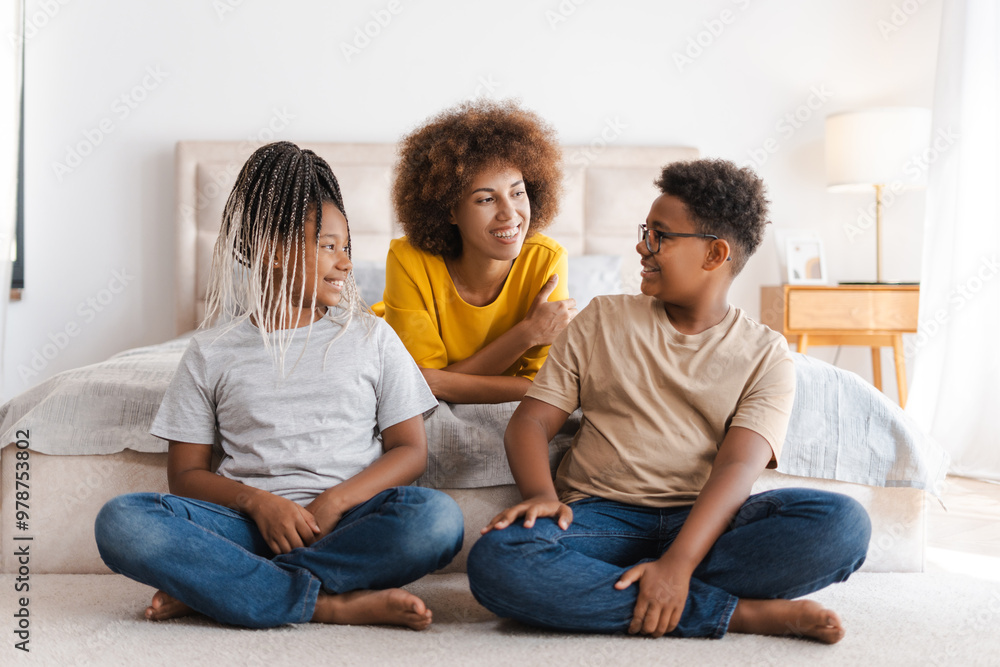 Happy African American young woman spending time with her two kids in bedroom Happy African American young woman spending time with her two kids in bedroom
