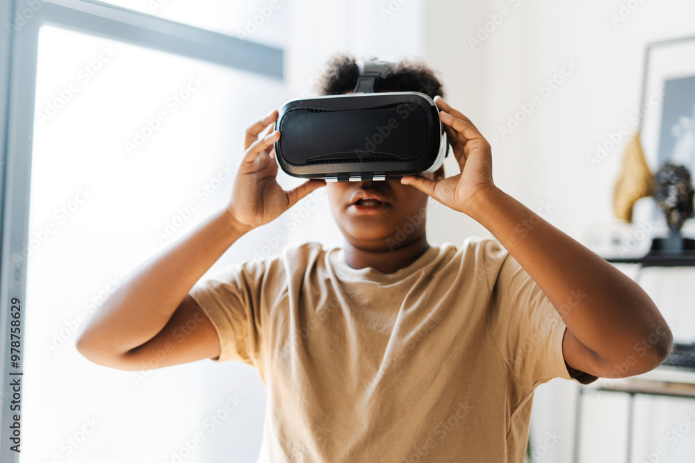 Amazed African American boy using VR headset while playing at futuristic game at home Amazed African American boy using VR headset while playing at futuristic game at home