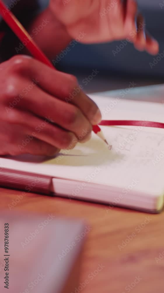 Vertical close up shot of hands of unrecognizable musician writing song lyrics in notebook at desk in neon lit studio Vertical close up shot of hands of unrecognizable musician writing song lyrics in notebook at desk in neon lit studio