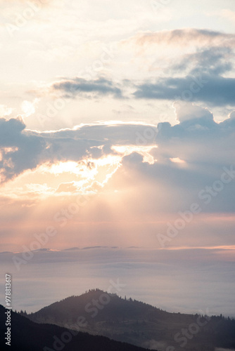 Majestic Mountain Landscape Covered in Mist with Sun Rays Breaking Through Clouds