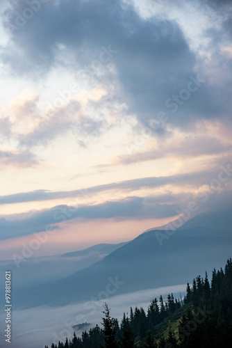 Majestic Mountain Landscape Covered in Mist with Sun Rays Breaking Through Clouds