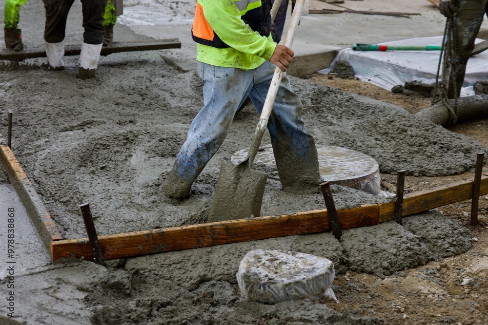 worker with shovel spreading wet concrete worker with shovel spreading wet concrete