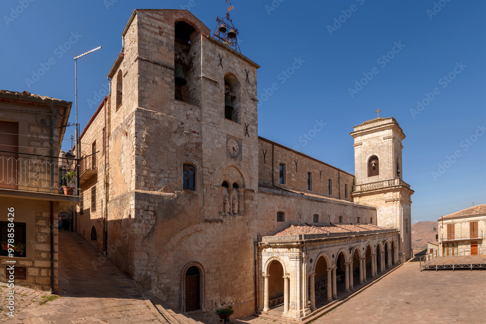 Panoramic view of Chiesa dei Santi Apostoli Pietro e Paolo in Petralia Soprana, Sicily, highlighting stone architecture, clock tower, and arched colonnade within village square under clear blue sky Panoramic view of Chiesa dei Santi Apostoli Pietro e Paolo in Petralia Soprana, Sicily, highlighting stone architecture, clock tower, and arched colonnade within village square under clear blue sky
