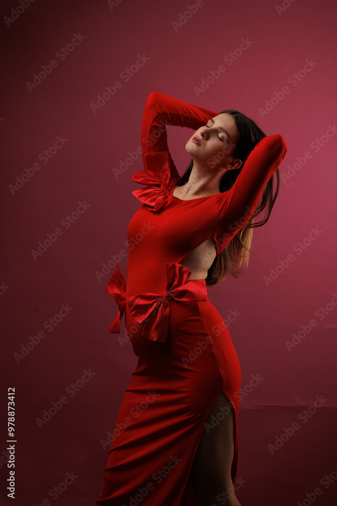 Beautiful young pregnant brunette girl. A woman waiting for a baby in a red dress with bows, on red background, in the studio. Beautiful young pregnant brunette girl. A woman waiting for a baby in a red dress with bows, on red background, in the studio.