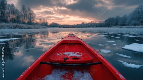 A vivid red kayak moves through tranquil icy waters under a cloudy sky. photo