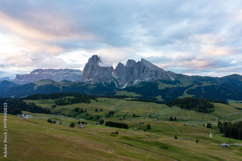 Aerial view of majestic dolomites and serene valley under a cloudy sky, Kastelruth, Italy. Aerial view of majestic dolomites and serene valley under a cloudy sky, Kastelruth, Italy.