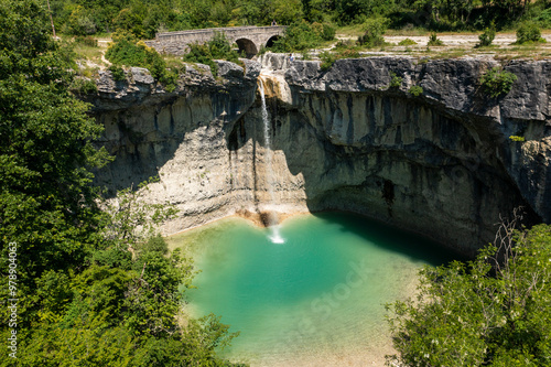 Aerial view of a breathtaking cascading waterfall in a lush green canyon surrounded by rugged cliffs and serene forest, Pican, Croatia. photo