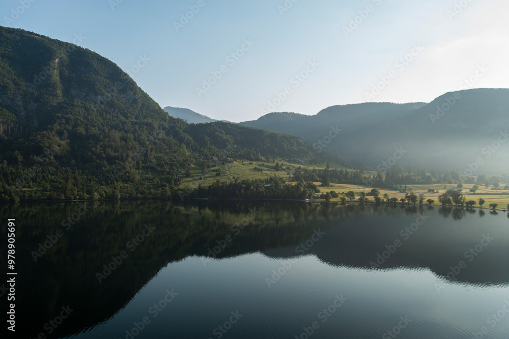 Aerial view of serene lake surrounded by majestic mountains and lush forests, Stara Fuzina, Slovenia. Aerial view of serene lake surrounded by majestic mountains and lush forests, Stara Fuzina, Slovenia.