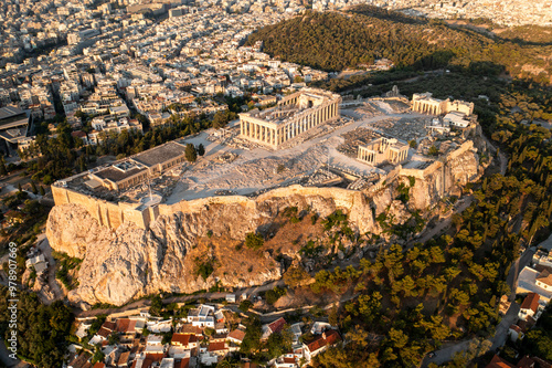 Aerial view of the historic acropolis with the parthenon and ancient ruins surrounded by a beautiful cityscape and trees, Athens, Greece.