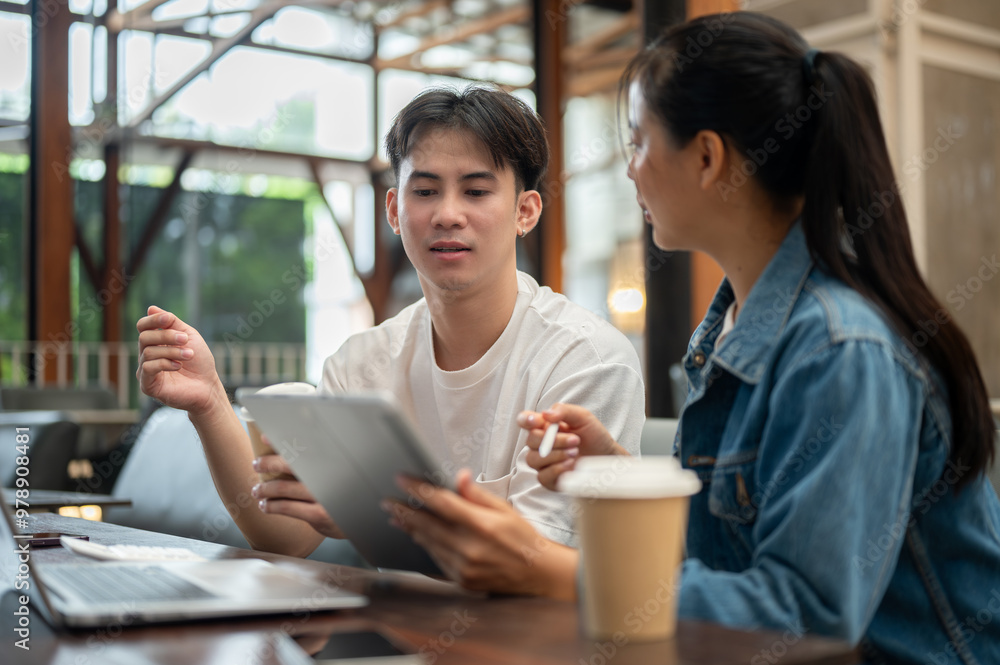 Two young Asian friends, a male and a female, are working remotely together from a coffee shop. Two young Asian friends, a male and a female, are working remotely together from a coffee shop.