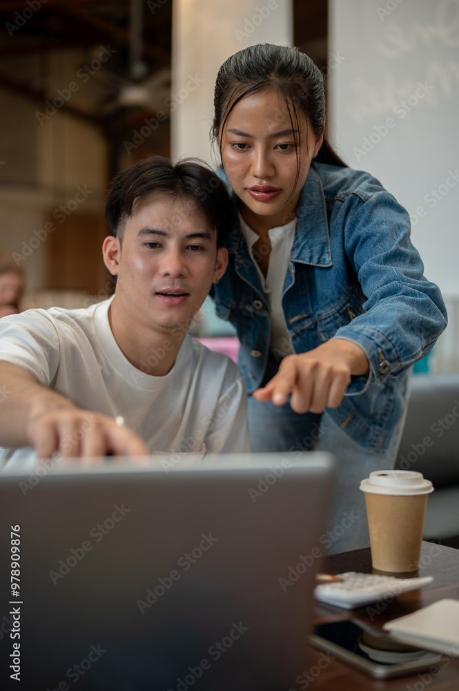 Two Asian friends or colleagues are in a coffee shop, discussing a project while working together. Two Asian friends or colleagues are in a coffee shop, discussing a project while working together.