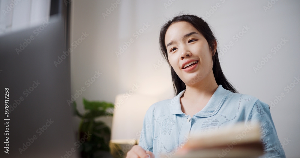 Portrait of Female freelancer holding a notebook explaining project in online meeting with team members via laptop in home office. Working from home, Remote working. Portrait of Female freelancer holding a notebook explaining project in online meeting with team members via laptop in home office. Working from home, Remote working.