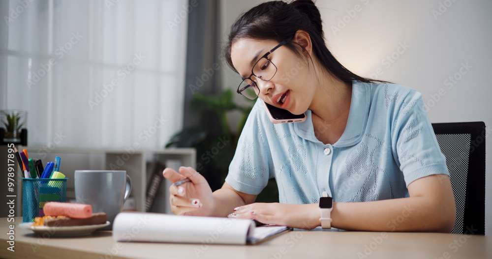 Portrait of Female freelancer sitting at desk explain work to co-workers via mobile phone in home office. Working from home Portrait of Female freelancer sitting at desk explain work to co-workers via mobile phone in home office. Working from home