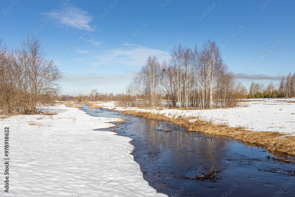 Obraz premium A river is frozen over with snow on the banks