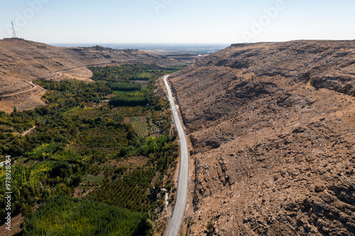 Aerial view of a beautiful winding road through a serene valley surrounded by mountains and greenery, Kalecik, Nusaybin, Mardin, Turkiye. photo