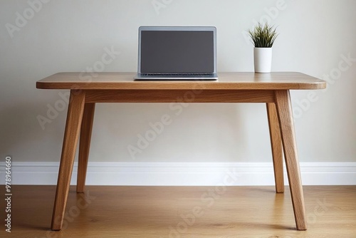 A wooden table with a laptop on it in front of a white wall.