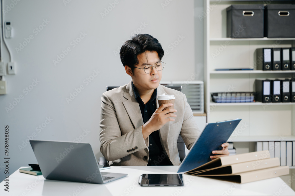 Young business man working at office with laptop, tablet and taking notes on the paper.. Young business man working at office with laptop, tablet and taking notes on the paper..