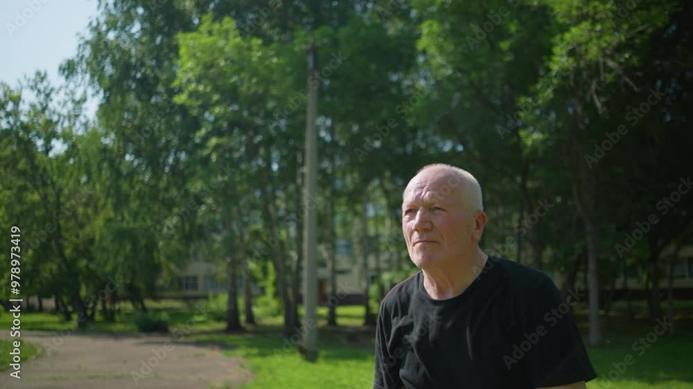 Close-up of an elderly man in a black shirt catching a ball throws it back, with a focused expression Close-up of an elderly man in a black shirt catching a ball throws it back, with a focused expression