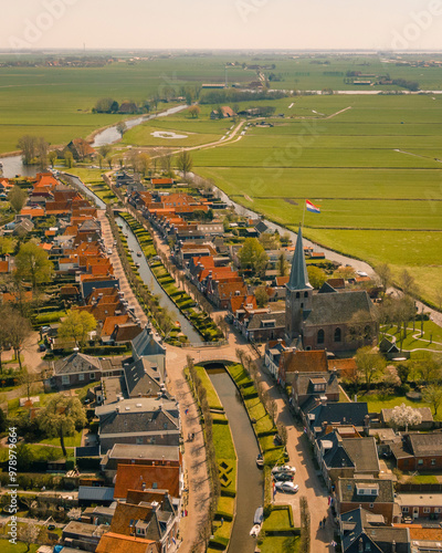 Aerial view of a picturesque village with a charming church and serene canals surrounded by green fields, Ijlst, Netherlands. photo