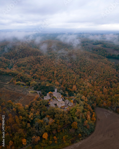 Aerial view of a majestic medieval castle surrounded by lush forests and moody clouds, Castello di Montalto, Tuscany, Italy. photo