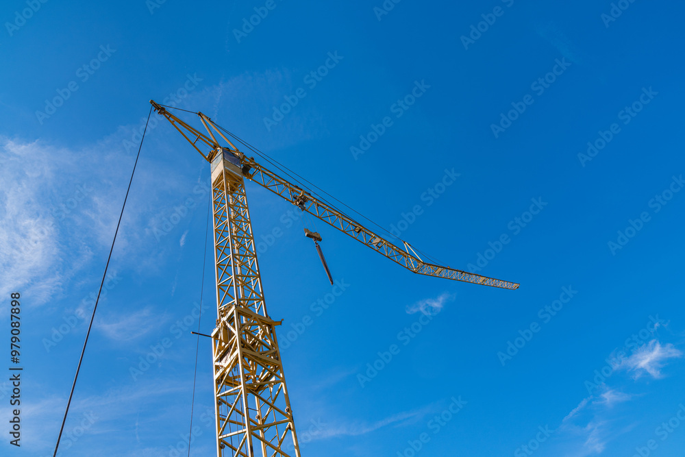 Construction crane towering over a bright blue sky at the site Construction crane towering over a bright blue sky at the site