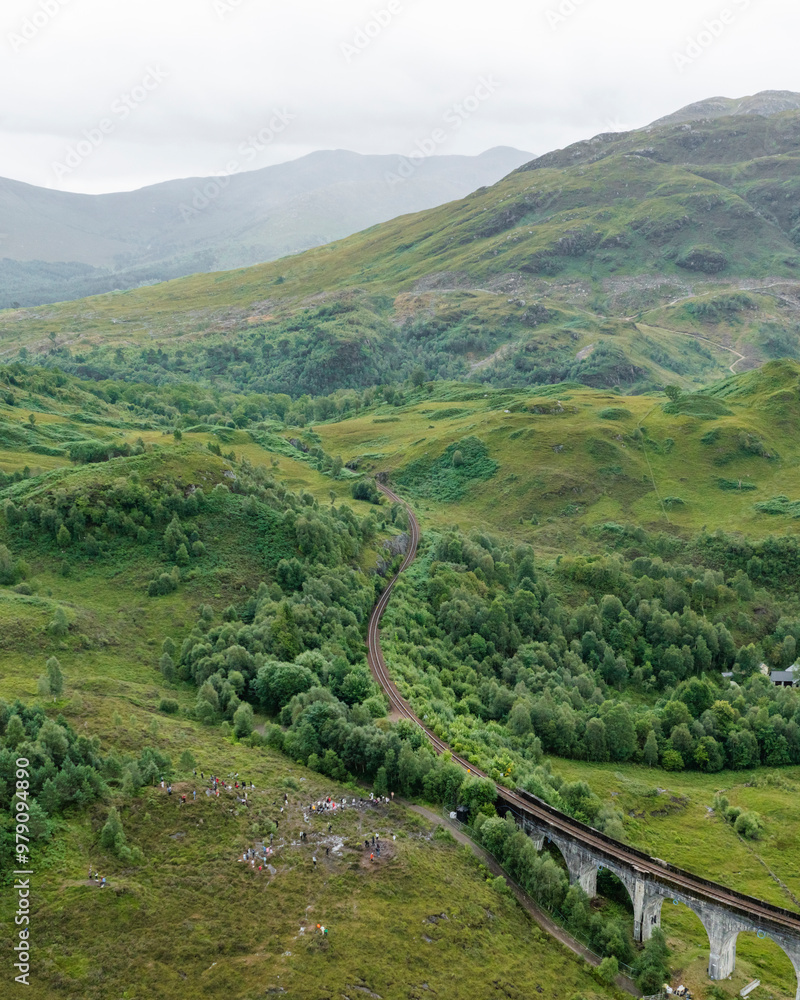 Aerial view of the majestic Glenfinnan Viaduct amidst lush greenery and winding river in the Scottish Highlands, United Kingdom. Aerial view of the majestic Glenfinnan Viaduct amidst lush greenery and winding river in the Scottish Highlands, United Kingdom.