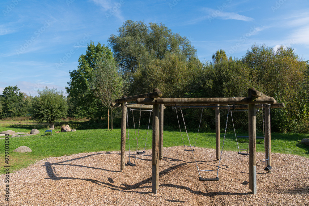 Swings in a secluded park surrounded by trees on a sunny day Swings in a secluded park surrounded by trees on a sunny day