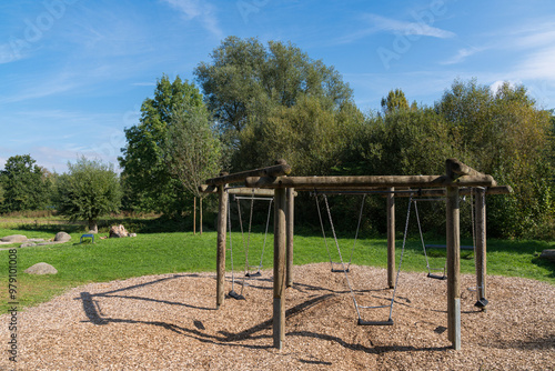 Swings in a secluded park surrounded by trees on a sunny day