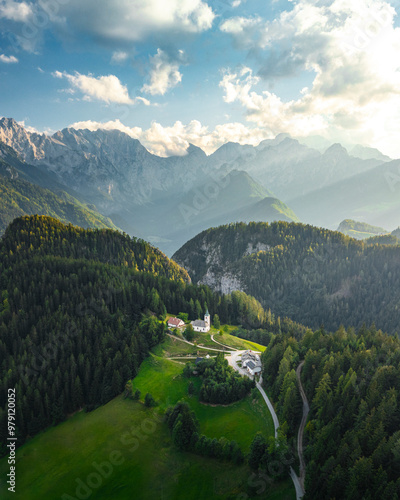 Aerial drone view of Cerkev Sv. Duh white church during sunset, mountains near Solčava, Slovenia photo