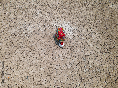 Aerial view of a woman collecting water in a drought-affected coastal village with cracked earth, Khulna, Bangladesh. photo