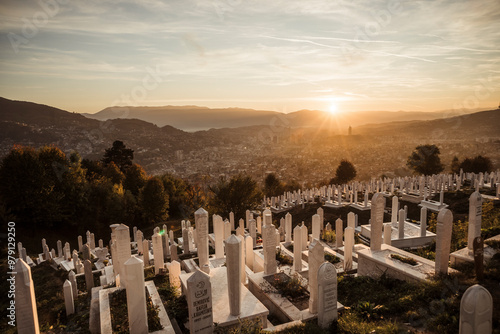 Aerial view of a serene graveyard with tombstones at sunset surrounded by mountains and cityscape, Stari Grad, Sarajevo, Bosnia and Herzegovina.