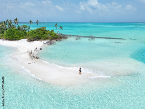 Aerial view of uninhabited Innafinolhu island with beautiful beach, turquoise lagoon, and palm trees, Haa Dhaalu, Maldives. photo