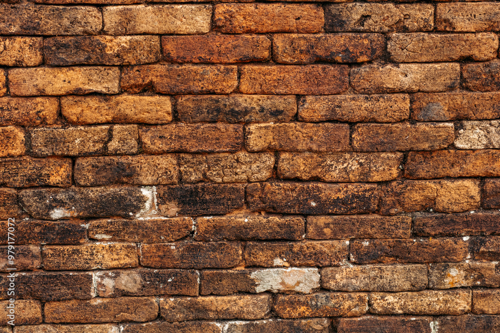 Naklejka premium Brown and orange weathered brick wall, textured surface suitable for backgrounds, textures, construction concepts, and rustic designs.