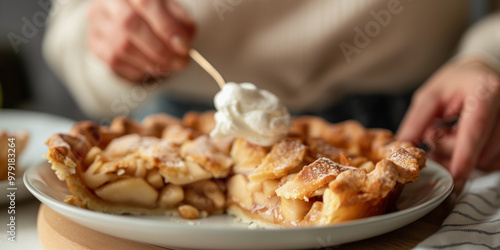 Woman spooning a dollop of whipped cream onto homemade apple pie